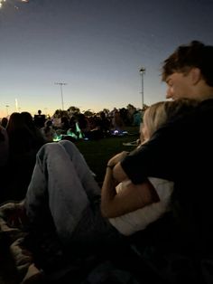 two people sitting on the grass watching fireworks