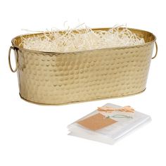 a large metal tub filled with lots of white shredded grass next to a package of tissue