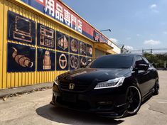 a black car parked in front of a yellow building