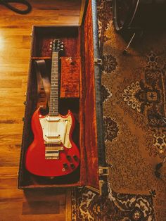 a red electric guitar in a wooden case