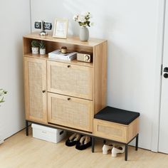 a wooden cabinet sitting next to a door with shoes on the floor and a plant