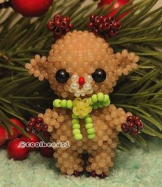 a beaded teddy bear sitting in front of christmas decorations