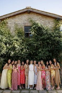 a group of women standing next to each other in front of a tree and building