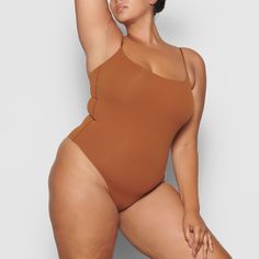 With its wide scoop neckline and low back providing the perfect foundation under clothing, this Cami Bodysuit is an essential wardrobe foundation. Features a high cut leg opening and thong back that remains invisible under clothing. Second-skin Scoop Neck Shapewear Swimwear, Beach Bodysuit With Smoothing Scoop Neck, Beach Bodysuit With Scoop Neck And Smoothing Details, Seamless Shapewear Swimwear With Scoop Neck, Scoop Back Bodysuit With Built-in Bra For Swimwear, Scoop Back Swimming Bodysuit With Built-in Bra, Scoop Back Bodysuit With Built-in Bra For Swimming, Beachwear Bodysuit With Lined Body And Low Back, Beachwear Bodysuit With Low Back