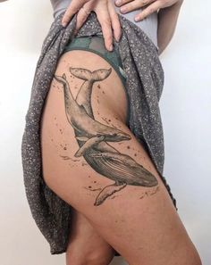 a woman's thigh with a whale tattoo on it