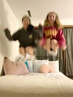 two girls jumping in the air on a bed