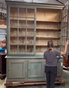 a woman standing in front of an old bookcase that is being painted blue and green