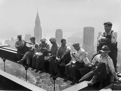 a group of men sitting on top of a tall building