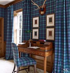 a desk and chair in a room with blue plaid curtains