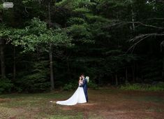 a bride and groom standing in the woods