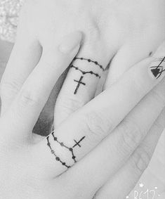 a person's hand with a cross tattoo on the middle finger and an arrow in the middle