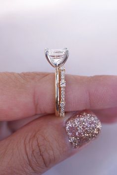 a woman's hand with a diamond ring on top of her finger and the other half of her wedding band