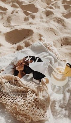 a book and drink on a towel in the sand