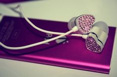 two earphones with pink and white crystals on them sitting on top of a purple case