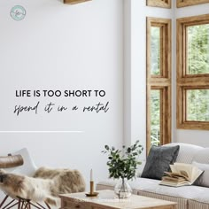 a living room filled with furniture next to two windows and a quote on the wall that says life is too short to spend it in a rental