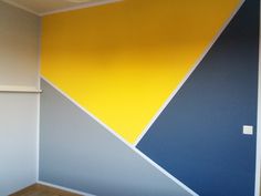 an empty room with yellow, blue and grey paint on the wall next to a window