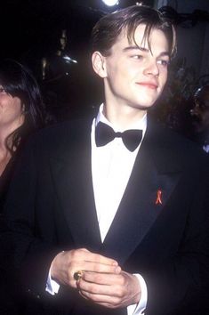 a young man in a tuxedo standing next to an older woman wearing a ring