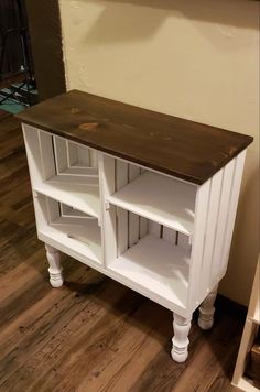 a white cabinet with shelves and drawers on the bottom, next to a wooden floor