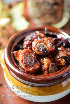 a bowl filled with meat and sauce on top of a wooden table next to an apple