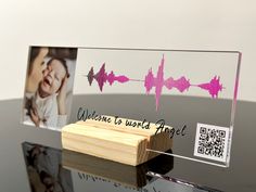 a wooden block with an image of a baby and sound wave on it, next to a photo frame