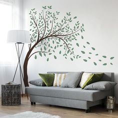 a living room with a couch and tree wall decal