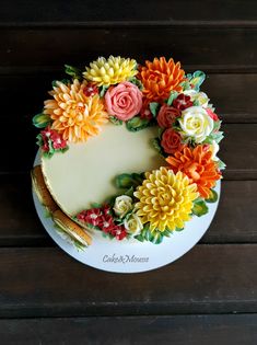 a cake decorated with flowers on top of a white plate next to a wooden table