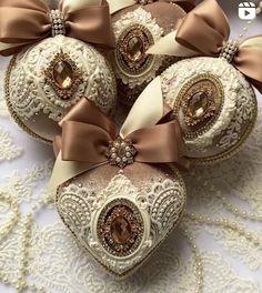 some ornaments are laying on a white lace table cloth with brown bows and ribbons around them