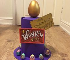 an egg sitting on top of a purple stand with candy bars around it and a sign that says wonka bar