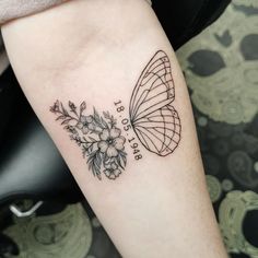 a butterfly and flowers tattoo on the left arm, with words written in cursive writing