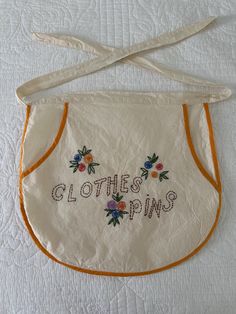 an embroidered apron with the words clothes pins written on it and orange trimmings