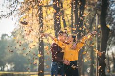 two children are playing with leaves in the park