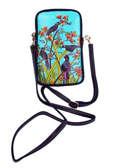 a blue purse with black birds on it and flowers in the background, hanging from a strap