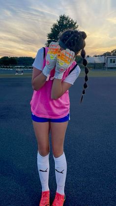 a girl in pink and blue is holding her hands up to her face while standing on the street