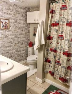 a bathroom with a toilet, sink and shower curtain in it's center area