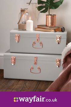 two pink suitcases sitting on top of each other next to a plant and candle