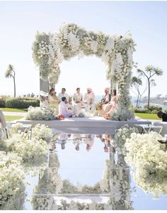 a group of people sitting on top of a lush green field next to a pool