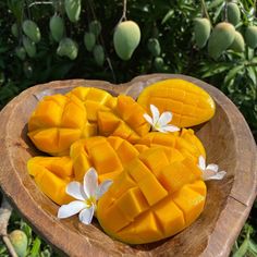 sliced mangos in a wooden bowl with white flowers