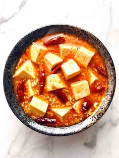 a bowl filled with tofu and sauce on top of a white counter