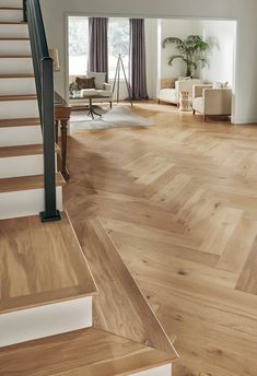 an open living room with wooden floors and white stairs leading up to the second floor