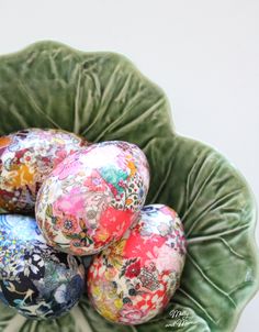 four decorated eggs in a green bowl on a table