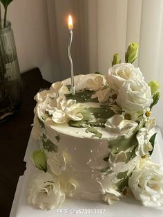 a white cake with flowers and a single candle