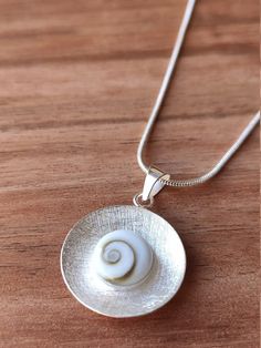 INFO - We really hope you are fine in these difficult times. We still working at home and for now the shipments are working normally. Big hugs from all our Team :)Handmade 925 Sterling silver shell necklace with a carefully polished Shiva Eye Shell.The shiva shell is into a sterling silver round with scratch finish.This a natural seashell also called "Ojo de Santa Lucia".This shell is the a perfect present for all those women who loves the sea and natural beauty.It is great for boho summer bride White Sterling Silver Shell Necklace For Gift, White Sterling Silver Shell Necklace As Gift, Silver Shell Necklace With Round Pendant For Gift, Silver Round Shell Necklace For Gifts, Shiva Pendant, Shiva Eye, Seashell Pendants, Silver Clay, Summer Bride