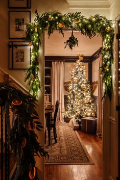 a decorated christmas tree sitting in the middle of a living room next to a doorway