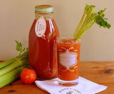 two jars filled with liquid sitting on top of a table next to celery