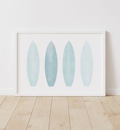 three blue surfboards are displayed in a white frame on a wooden floor next to a wall