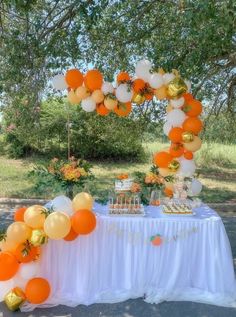 an orange and white dessert table with balloons