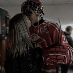 a man and woman kissing while wearing hockey gear