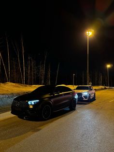 two cars parked on the side of a road at night