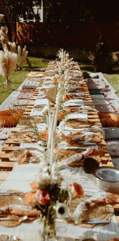 a long table is set up with plates and silverware for an outdoor dinner party