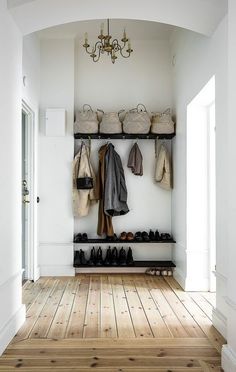 an entryway with shoes and coat racks on the wall, chandelier above